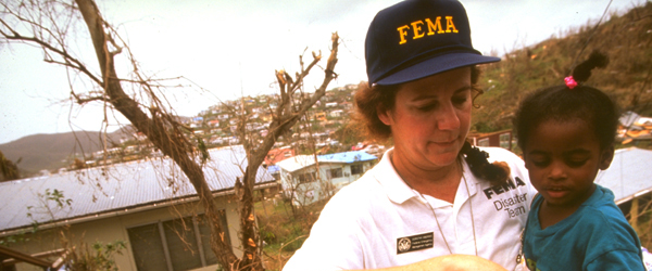 Una trabajadora de FEMA retira a un niño de la zona de desastre.